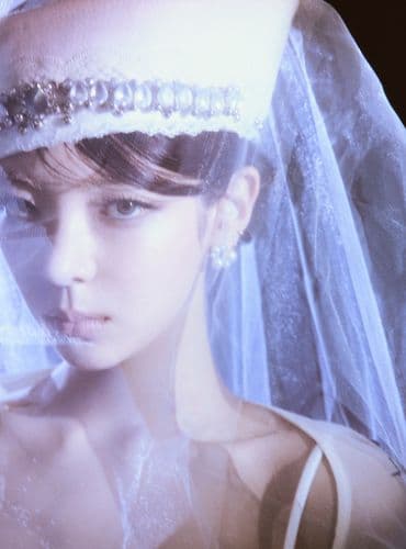 Close-up of a woman's face and white embellished hat with a sheer veil.